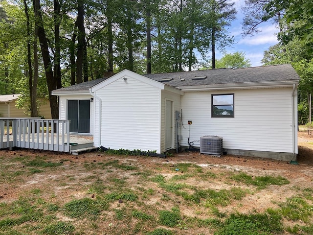 back of house featuring central AC, a deck, and a lawn