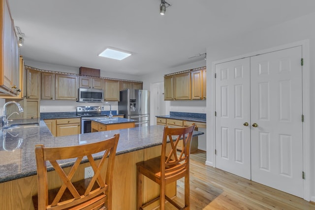 kitchen featuring a kitchen breakfast bar, stainless steel appliances, sink, light hardwood / wood-style flooring, and a kitchen island