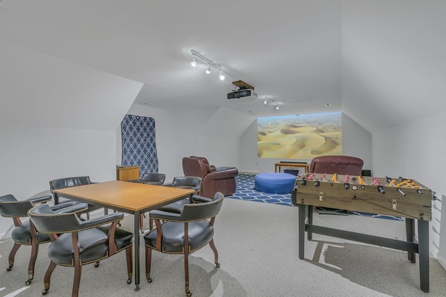 dining area with rail lighting, light colored carpet, and vaulted ceiling