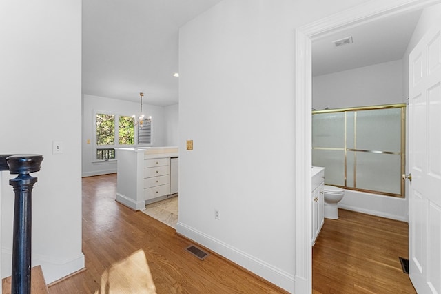 hall with light hardwood / wood-style floors and a notable chandelier