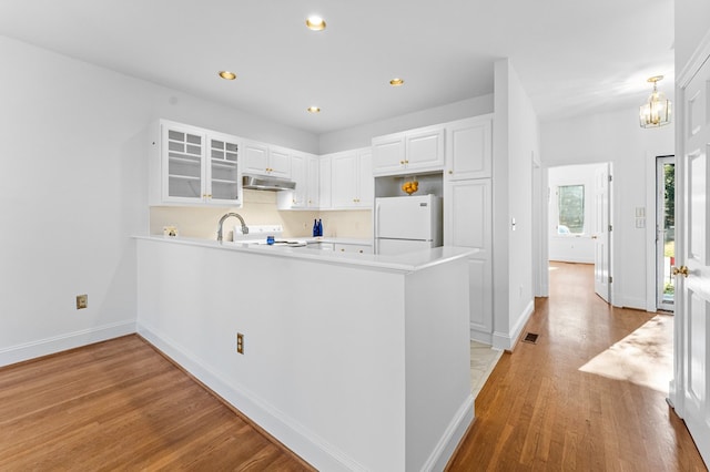 kitchen with stove, white cabinets, white refrigerator, light hardwood / wood-style floors, and kitchen peninsula