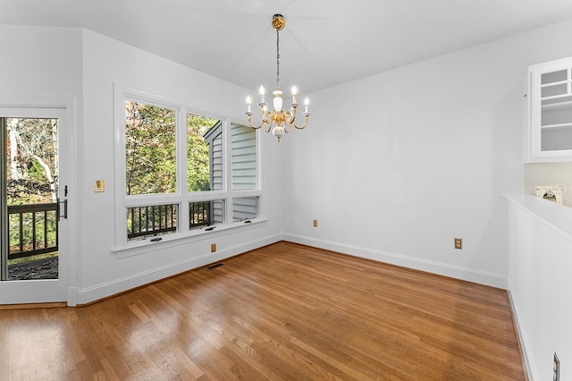 unfurnished dining area featuring plenty of natural light, hardwood / wood-style floors, and an inviting chandelier