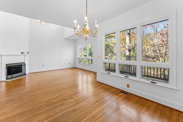 unfurnished living room featuring a notable chandelier, a healthy amount of sunlight, and light hardwood / wood-style floors