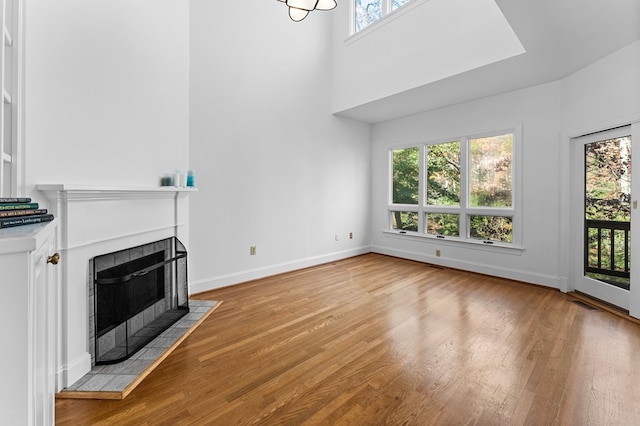 unfurnished living room with a tiled fireplace and light wood-type flooring