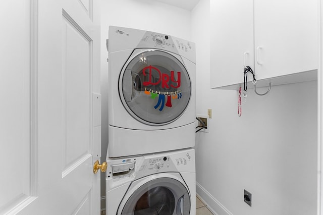 laundry area featuring cabinets and stacked washer and dryer