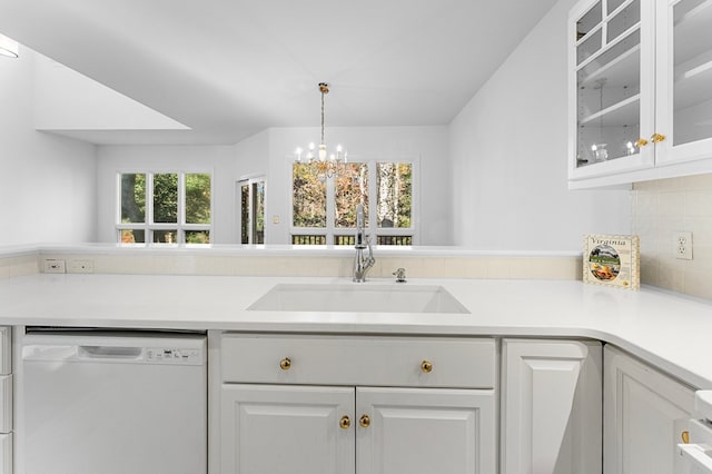 kitchen featuring white dishwasher, sink, decorative light fixtures, white cabinetry, and a chandelier