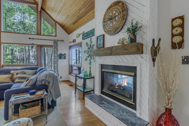 living room with a large fireplace, wooden ceiling, high vaulted ceiling, beamed ceiling, and light wood-type flooring