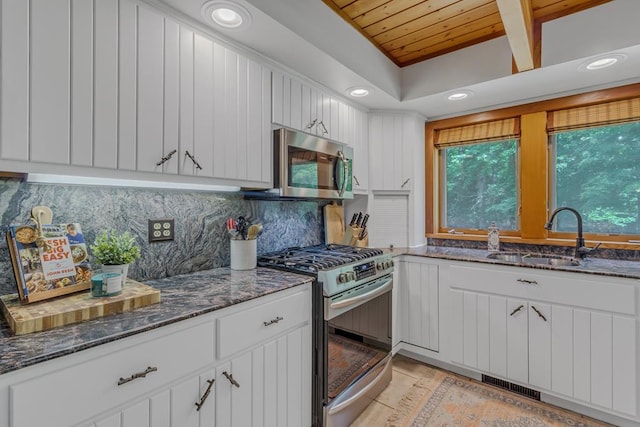 kitchen featuring backsplash, sink, dark stone countertops, appliances with stainless steel finishes, and white cabinetry