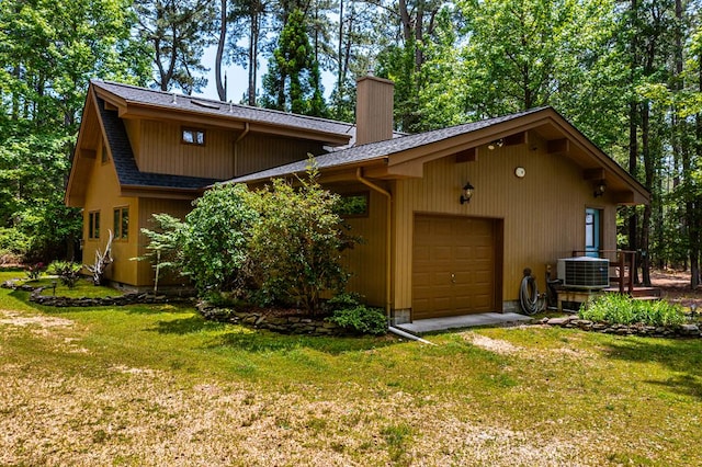 exterior space featuring a garage, a yard, and central AC