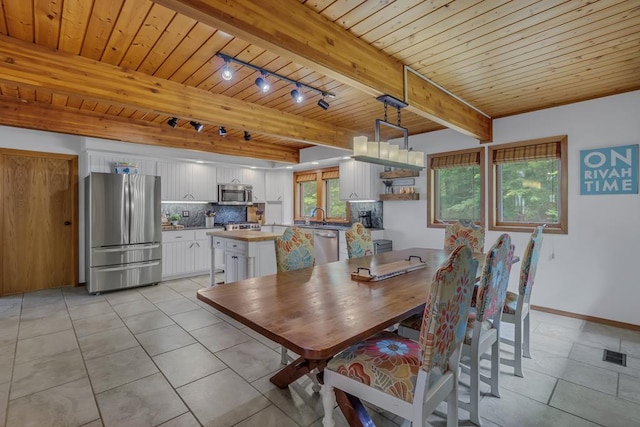 dining space featuring beam ceiling, sink, light tile patterned floors, and wood ceiling