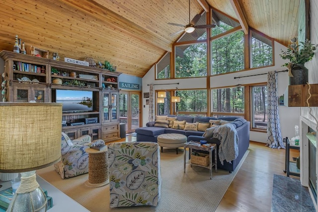 living room with hardwood / wood-style floors, a high end fireplace, high vaulted ceiling, ceiling fan, and beamed ceiling