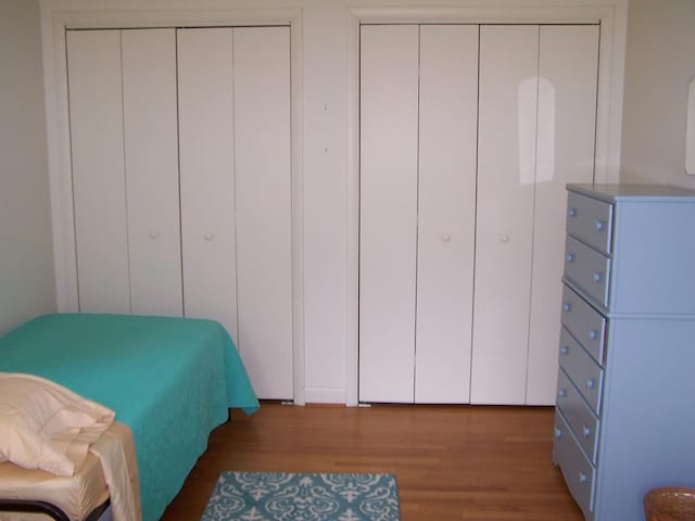 bedroom featuring multiple closets and dark wood-type flooring