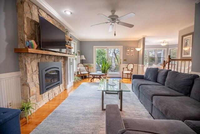 403 Moores Creek Dr, Deltaville, VA 23043 - living area featuring a stone fireplace, light wood-type flooring, crown molding, ceiling fan, and a wainscoted wall
