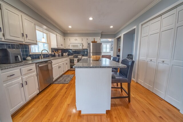 403 Moores Creek Dr, Deltaville, VA 23043 - kitchen featuring appliances with stainless steel finishes, a kitchen bar, a kitchen island, plenty of natural light, and crown molding