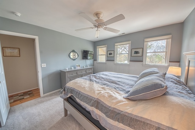403 Moores Creek Dr, Deltaville, VA 23043 - bedroom featuring light carpet, ceiling fan, a wainscoted wall, and baseboards