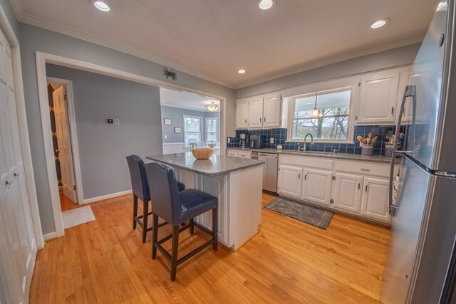 403 Moores Creek Dr, Deltaville, VA 23043 - kitchen featuring appliances with stainless steel finishes, a center island, white cabinets, a breakfast bar area, and light wood-style floors