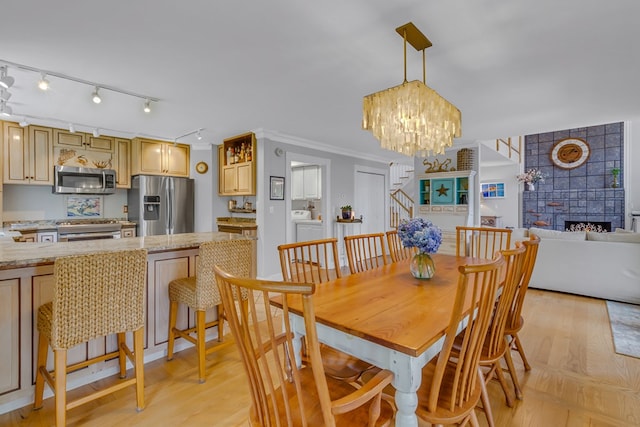 324 Bayberry Ln, Reedville, VA 22539 - dining area with light wood-style flooring, washing machine and dryer, a fireplace, and track lighting