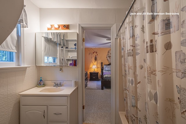 bathroom with shower / bath combination with curtain, vanity, and tile walls