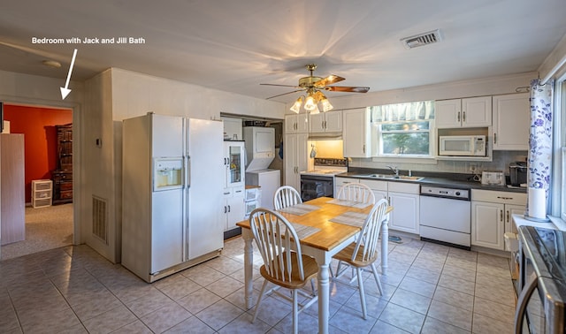 kitchen with white cabinetry, sink, white appliances, and stacked washer and dryer