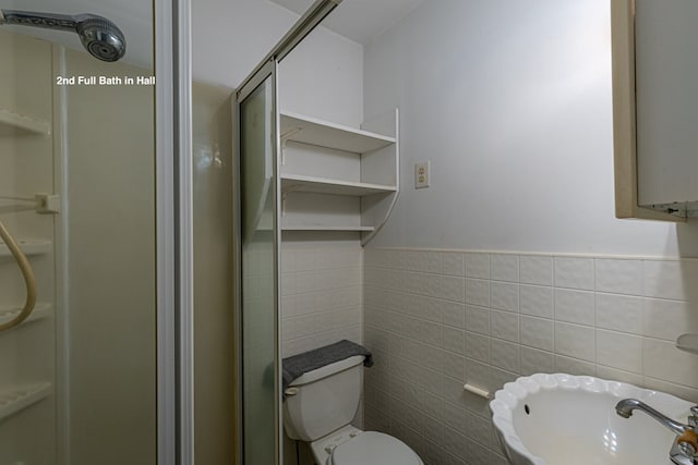 bathroom featuring toilet, tile walls, and walk in shower