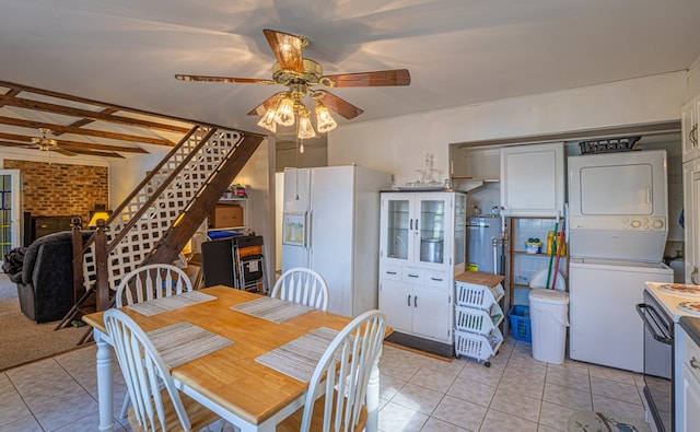 dining room with stacked washer / dryer, ceiling fan, light tile patterned floors, and brick wall