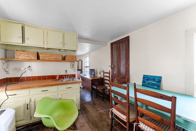 kitchen featuring light countertops, open shelves, dark wood finished floors, cream cabinetry, and a sink