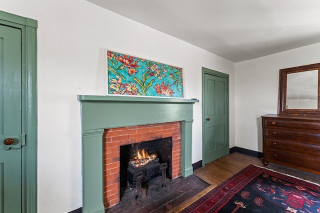 living room featuring baseboards, wood finished floors, and a brick fireplace