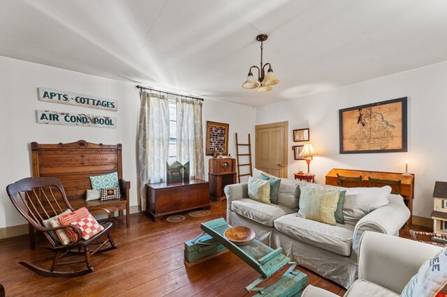 living room featuring an inviting chandelier, baseboards, and wood-type flooring