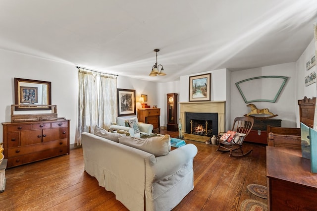 living room with a lit fireplace and dark wood-style flooring