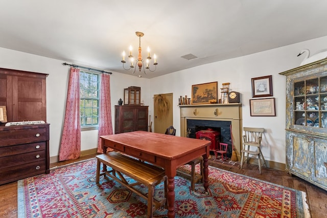 dining space featuring a fireplace with flush hearth, visible vents, baseboards, wood finished floors, and an inviting chandelier