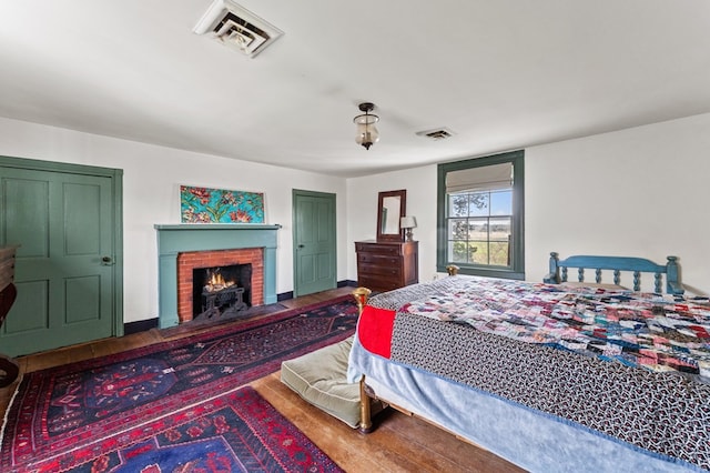 bedroom featuring baseboards, visible vents, wood finished floors, and a fireplace
