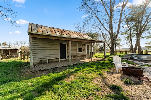 back of house with a standing seam roof, fence, metal roof, a fire pit, and a yard