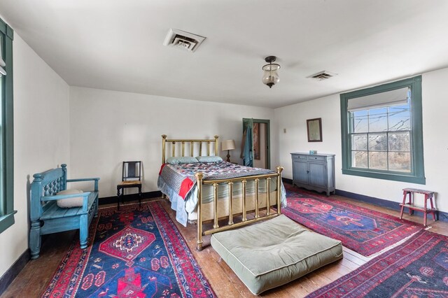 bedroom with baseboards, visible vents, and wood finished floors