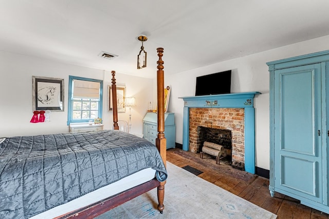 bedroom featuring dark wood finished floors, a fireplace, and visible vents