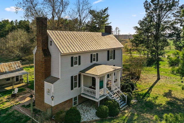 view of front of home featuring a porch, stairs, and a chimney