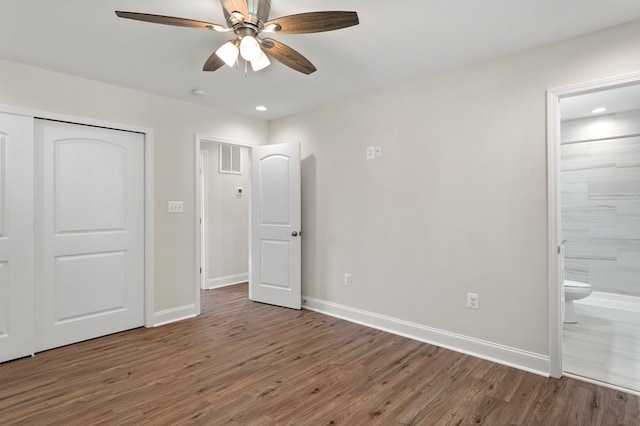 unfurnished bedroom with ceiling fan, wood-type flooring, and ensuite bath