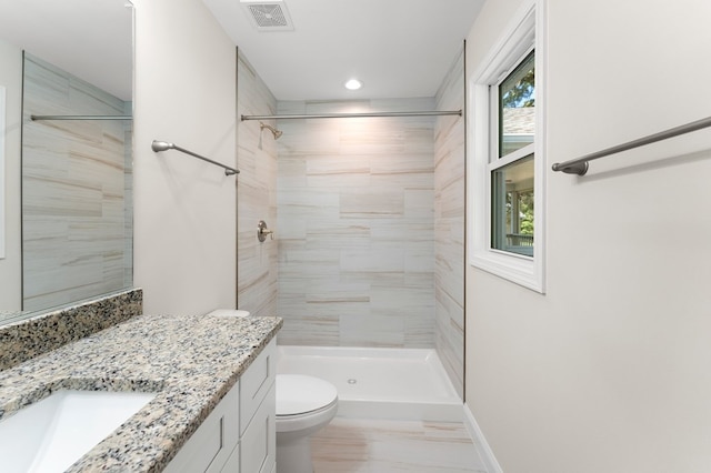 bathroom with vanity, toilet, and a tile shower