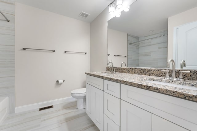 bathroom with a tile shower, vanity, and toilet