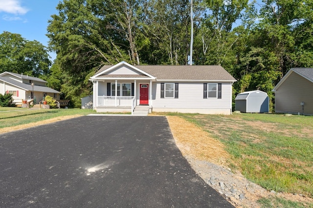 view of front of property with a storage unit, covered porch, and a front yard