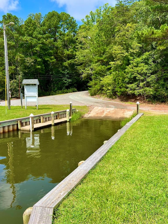 view of dock with a water view and a yard