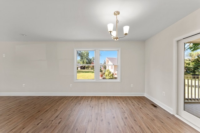 empty room with light hardwood / wood-style floors and an inviting chandelier