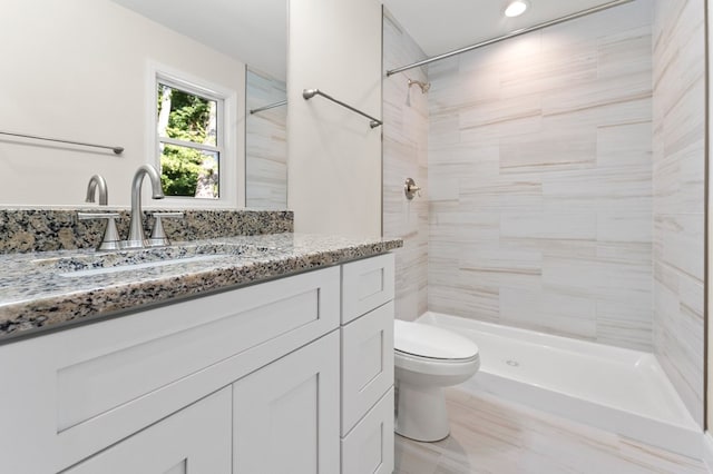 bathroom with vanity, toilet, and a tile shower