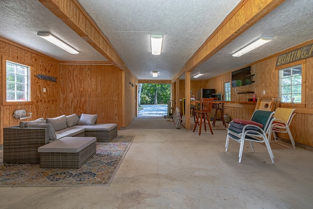 living room with a wealth of natural light, wood walls, and concrete flooring