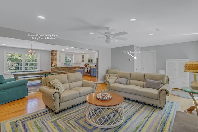 living room featuring light hardwood / wood-style floors and ceiling fan with notable chandelier