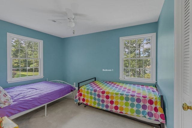 carpeted bedroom with ceiling fan and multiple windows