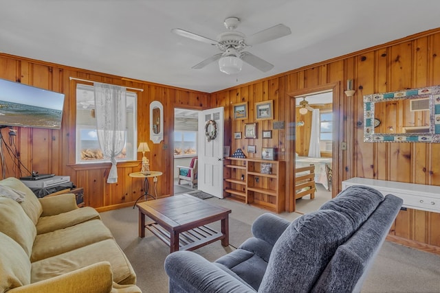 living room with light carpet, ceiling fan, and wood walls