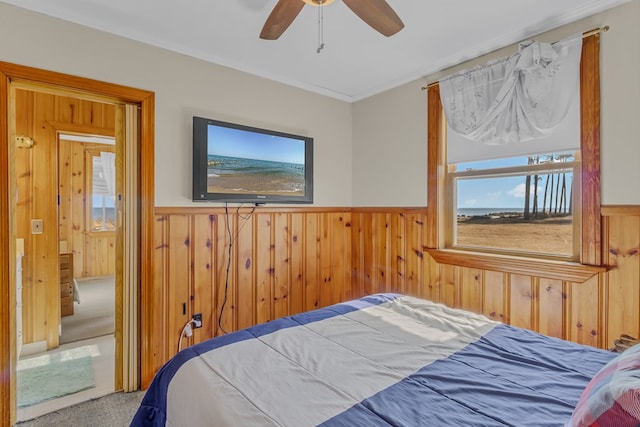 bedroom featuring ceiling fan, carpet, crown molding, and wooden walls