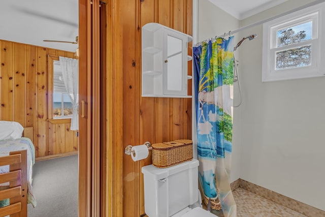 bathroom with ceiling fan, curtained shower, wooden walls, and toilet