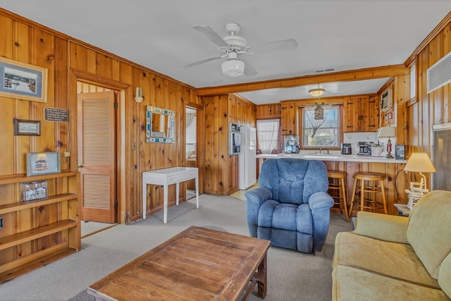 living room featuring light carpet, ceiling fan, and wood walls