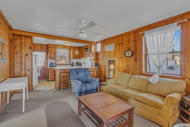 living room featuring light carpet, ceiling fan, and wood walls